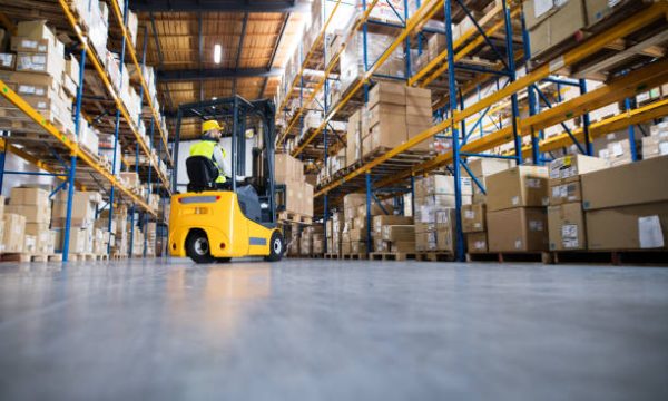 Prodaja baterije za viljuskare4 Young male worker lowering a pallet with boxes. Forklift driver working in a warehouse.